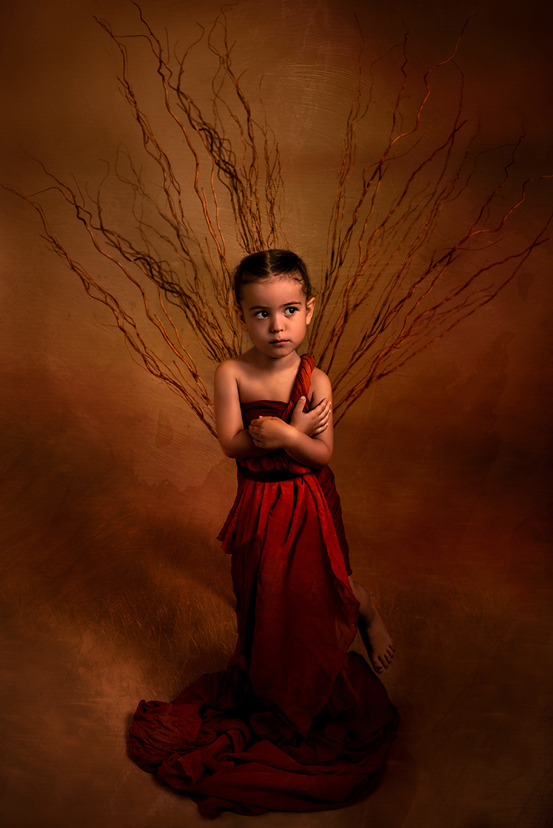 Ritratto fine art bambina con treccia e vestito rosso su sfondo marrone