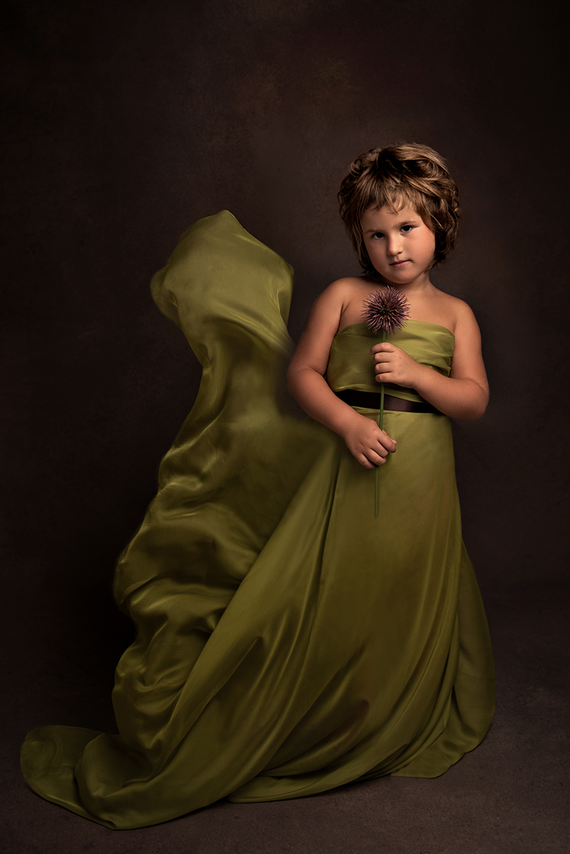 Ritratto bambina capelli corti con vestito verde e svolazzo con un bel fiore viola in mano