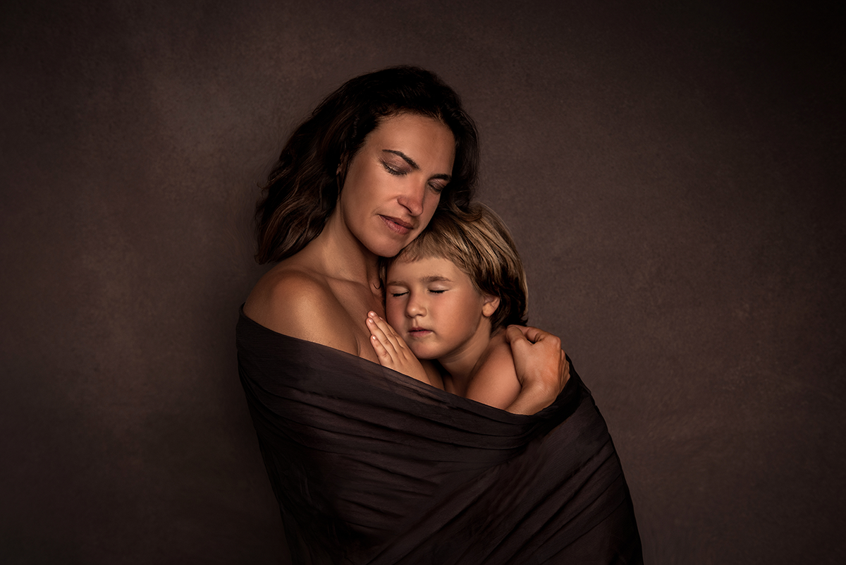Ritratto di madre con bambina avvolte da tulle su sfondo marrone