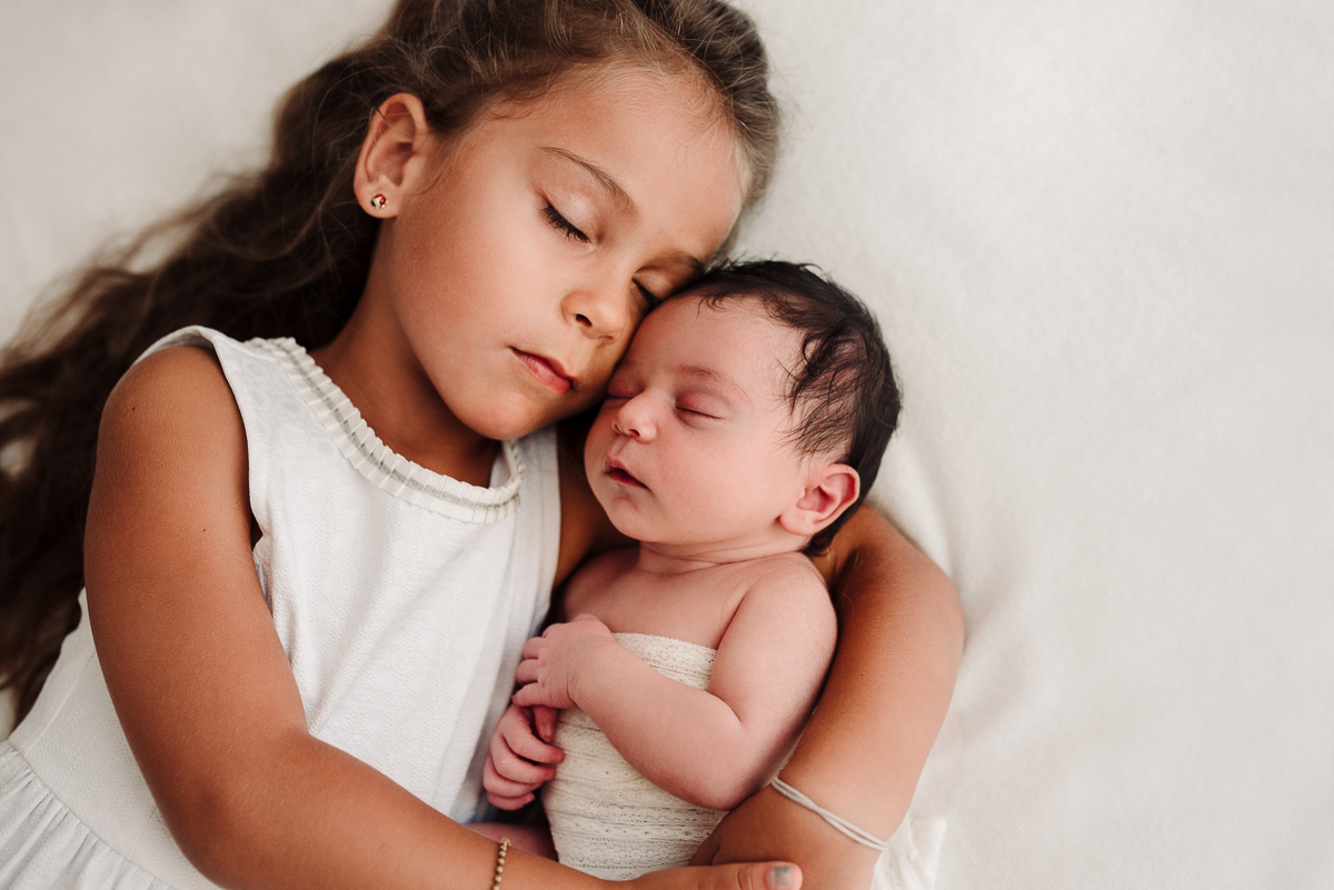 Newborn sorella e neonata abbracciate ad occhi chiusi