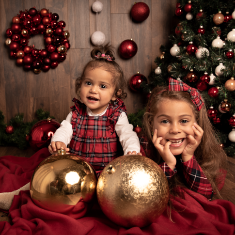 Natale sorelle giocano con le decorazioni natalizie sotto l'albero di natale